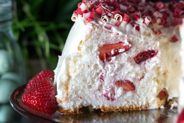 Fluffy Angel Food Cake stuffed with strawberries and whipped cream. Frosted with a cream cheese frosting. This recipe shows you exactly how to stuff this cake. So easy but so impressive. People will want to know how you did it.