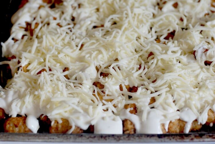 Tater Tots On A Pan With Shredded Cheese Spread On Them