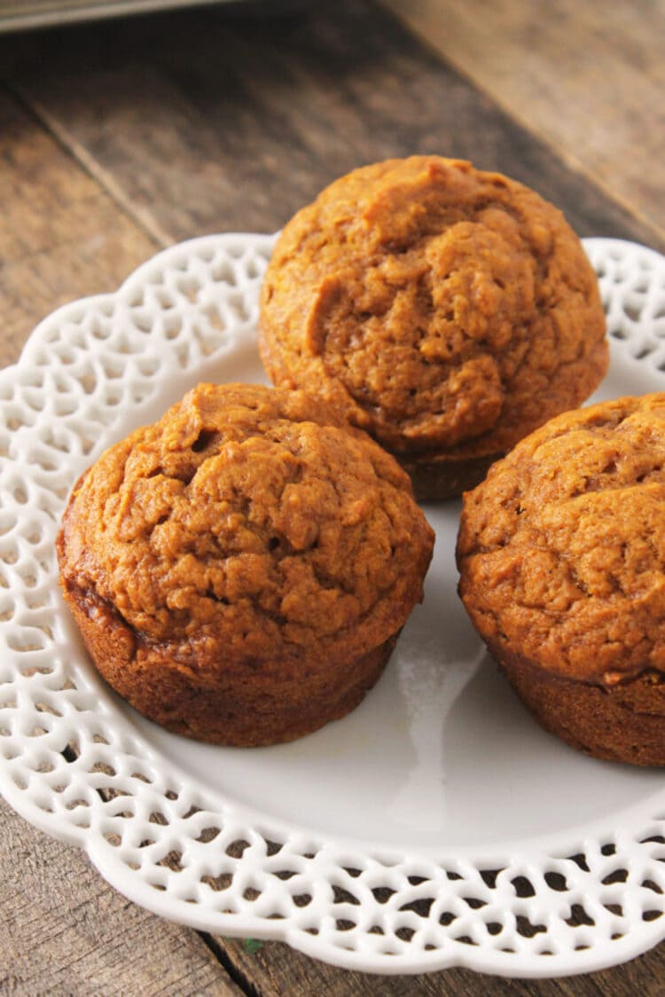 Three ready to eat pumpkin muffins displayed on a white plate