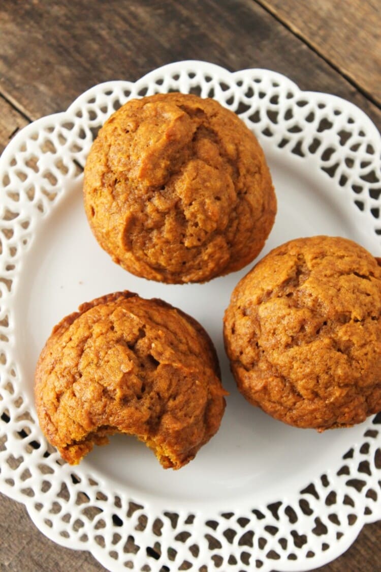 Close up photo of three ready to eat muffins on a white plate with one muffin having a bite mark