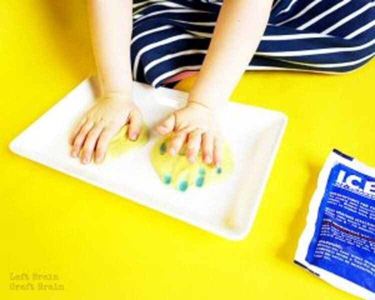 science project color changing slime, two hand touching a color changing slime on a yellow background