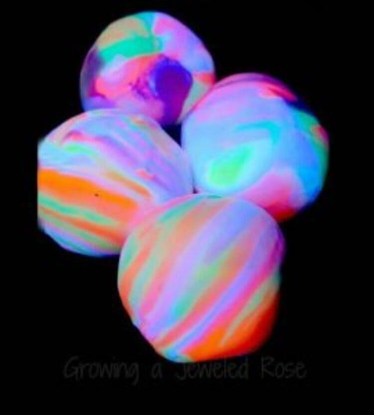 science project for kids four glowing balls in the dark in bright neon colors on a black background