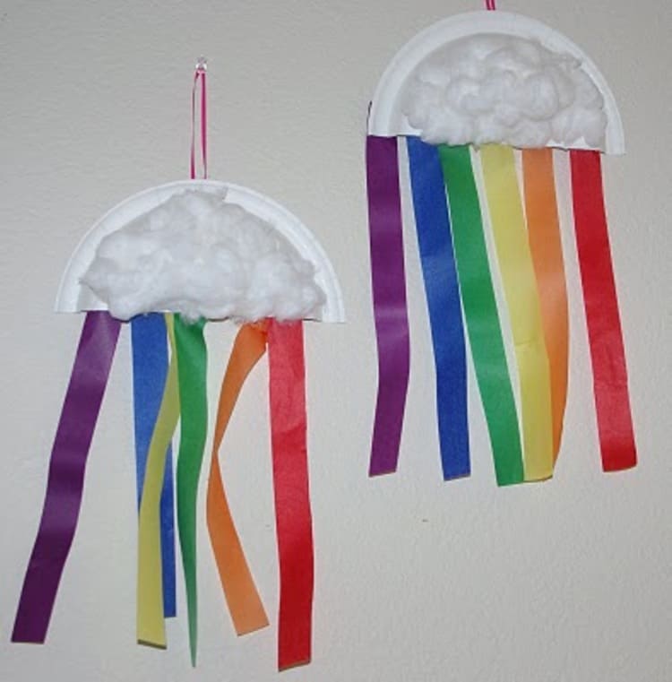 paper plate craft rainbows hang from a white wall with purple, blue, green, yellow, orange, red colors 