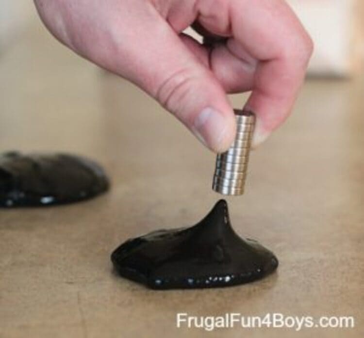 science project black magnetic slime and a hand holding a magnet