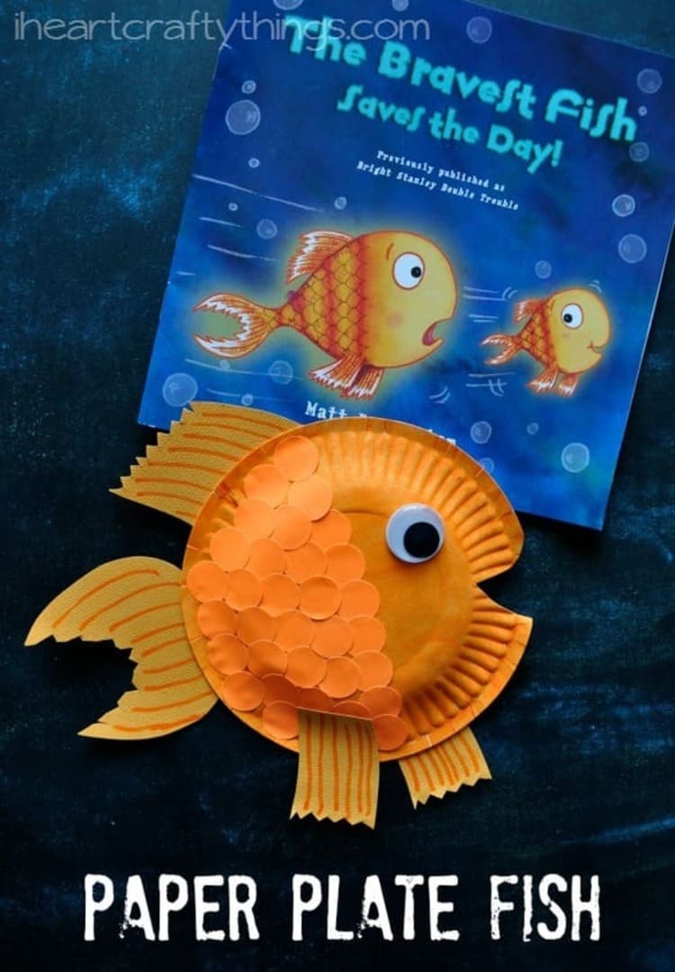 paper plate craft orange fish with a book next to it on a dark blue background