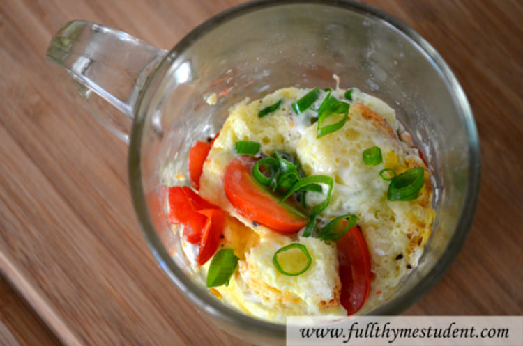 microwave mug snacks quiche in the making in a transparent glass cup with chopped tomatoes