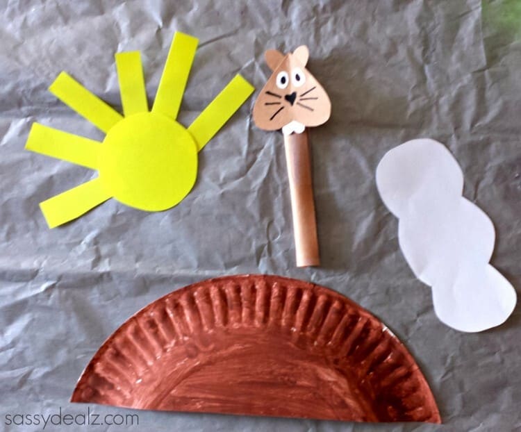 paper plate craft groundhog day with a sun and a cloud on a grey background