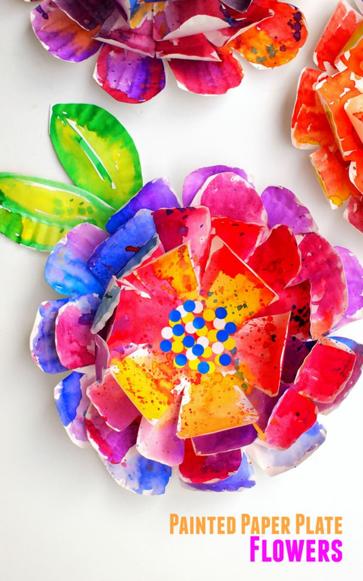 paper plate craft painted flower in red, blue, purple, yellow with green and yellow leaves, on a white background