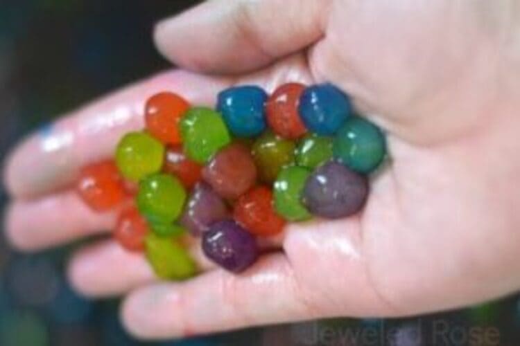 Edible water beads of different colors held in the palm of a hand