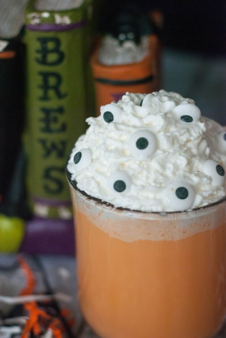 Tricky brew orange Halloween Hot Chocolate in classic cocoa mug with whipped cream and eyeballs