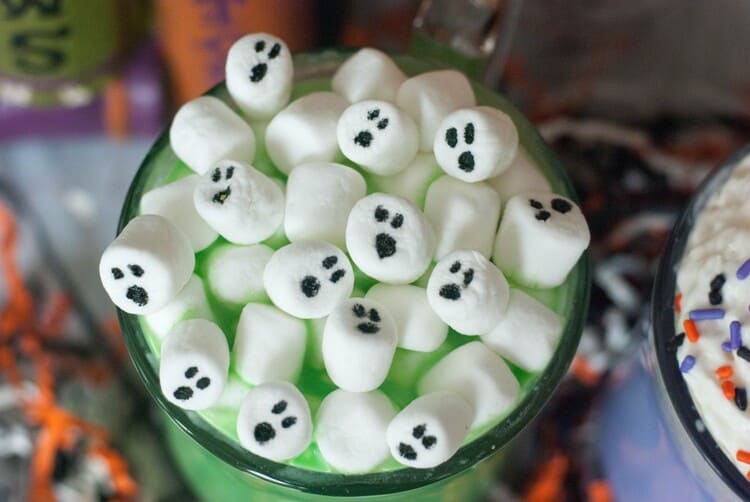 White Marshmallow ghosts atop a spooky green mug f Halloween hot Chocolate