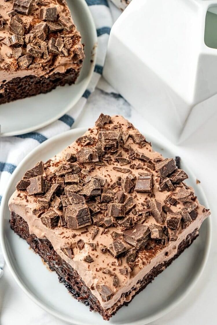 Huge squares of Chocolate Pudding Poke Cake on clean white plates.