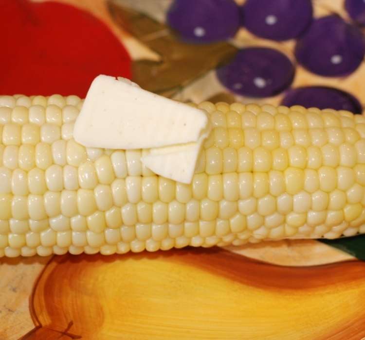 Corn on the cob and melting butter slices on a bright festive plate
