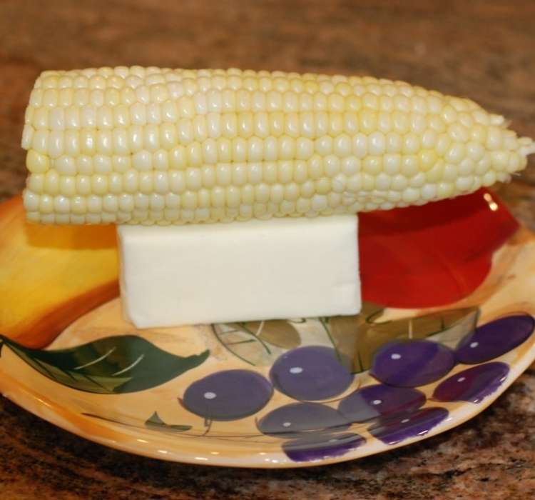 Corn on the cob sitting on a festive plate topped with a stick of butter