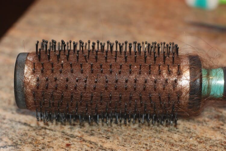 clean your hairbrush in minutes, a a round hairbrush with old hair buildup on a flat surface