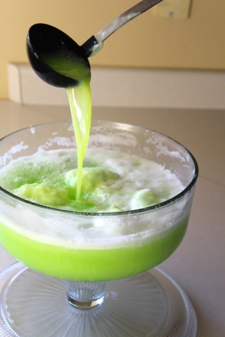 polyjuice potion recipe, a green colored drink in a transparent glass with a black ladl
