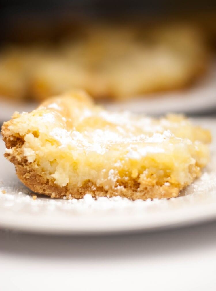 close up photo of a slice of ooey gooey butter cake on a white plate