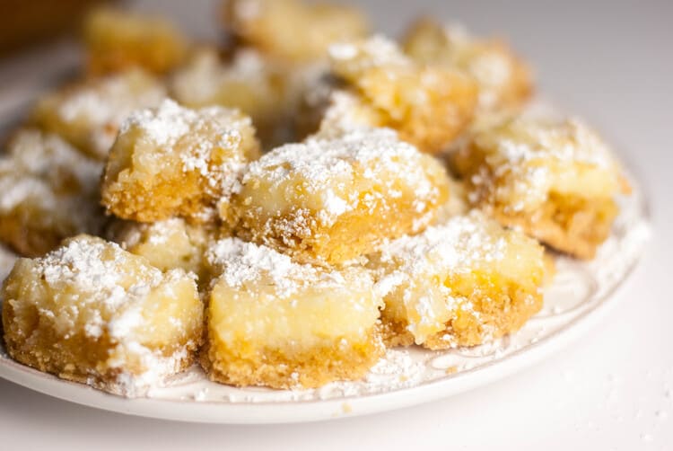 ooey gooey butter cakes on a white plate with powdered sugar sprayed over the cakes